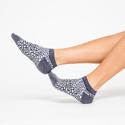 woman wears a pair of grey socks with navy and grey leopard pattern on the socks