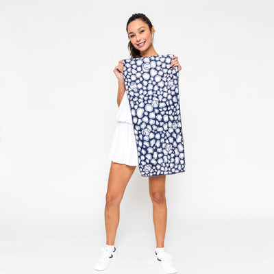 woman holds up Rectangular towel with navy and grey repeating leopard pattern with tennis balls icons printed over the leopard.