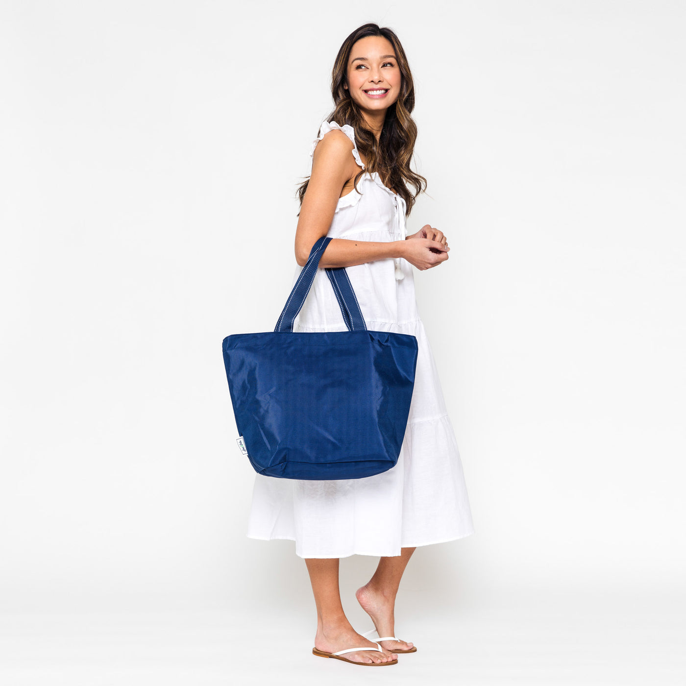 woman holding navy nylon tote over elbow