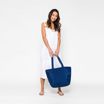 woman holding navy nylon tote bag with navy straps at her feet