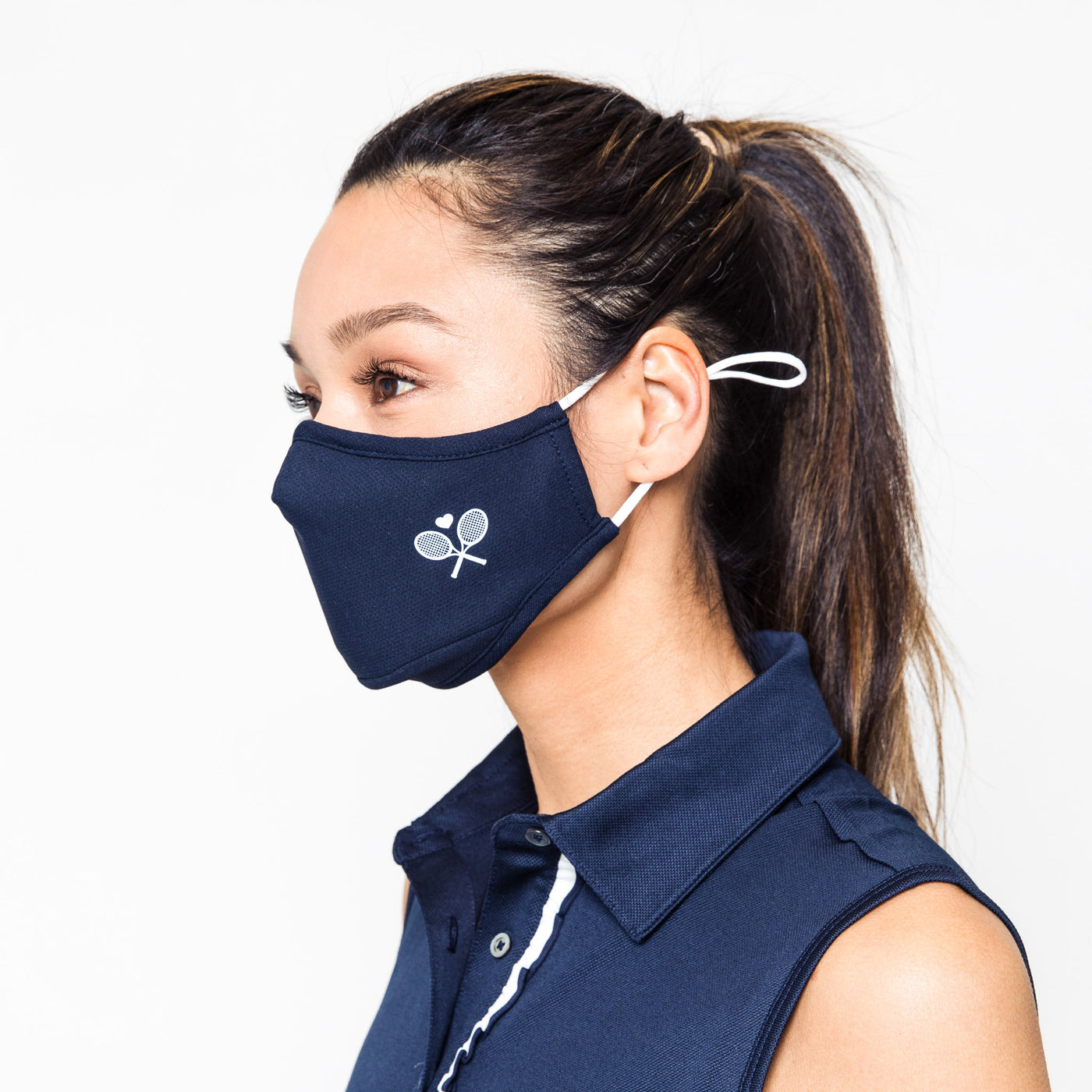 woman wears navy face mask with white crossed racquets printed on one side