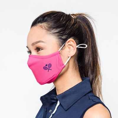 woman wears hot pink face mask with navy crossed racquets printed on one side
