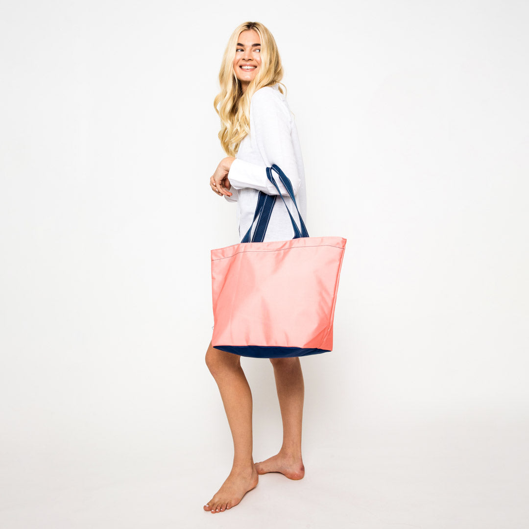 woman wearing coral nylon tote bag with navy straps