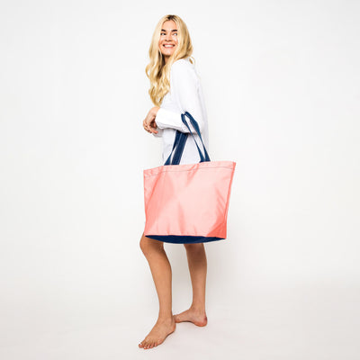woman wearing coral nylon tote bag with navy straps