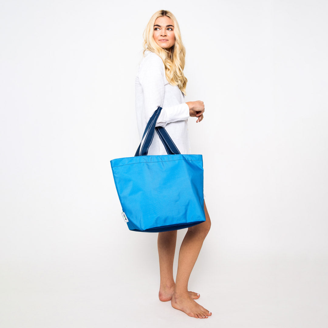 woman holding blue nylon tote bag over her elbow