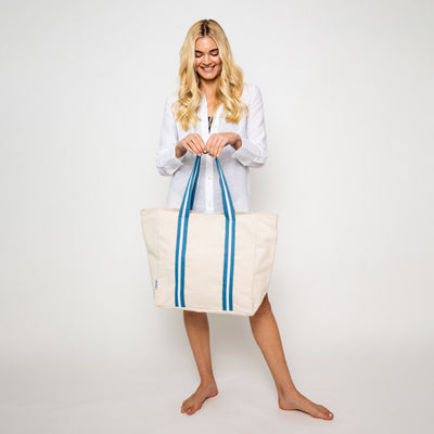 woman holding natural canvas tote with blue and white cotton webbing straps
