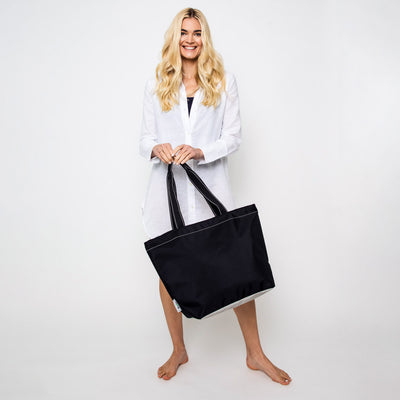 woman holding black nylon tote with black straps 