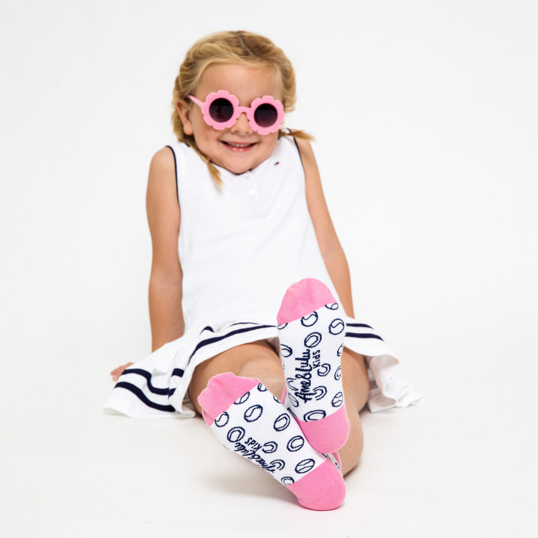 girl wearing pair of white kids socks with pink heel and toes with navy tennis balls stitched on socks