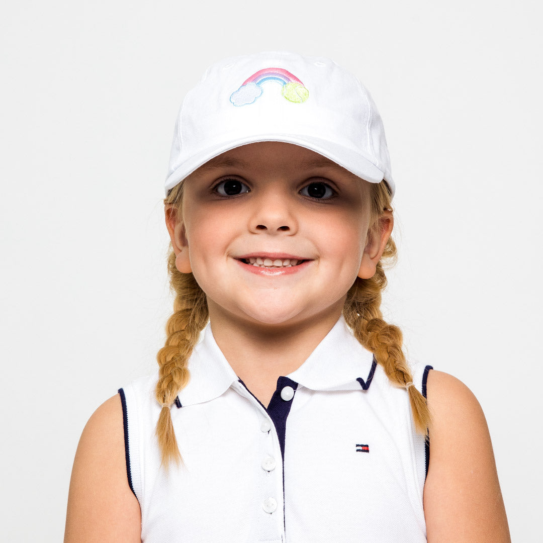Little girl wearing white kids baseball hat with rainbow and tennis ball embroidered on front