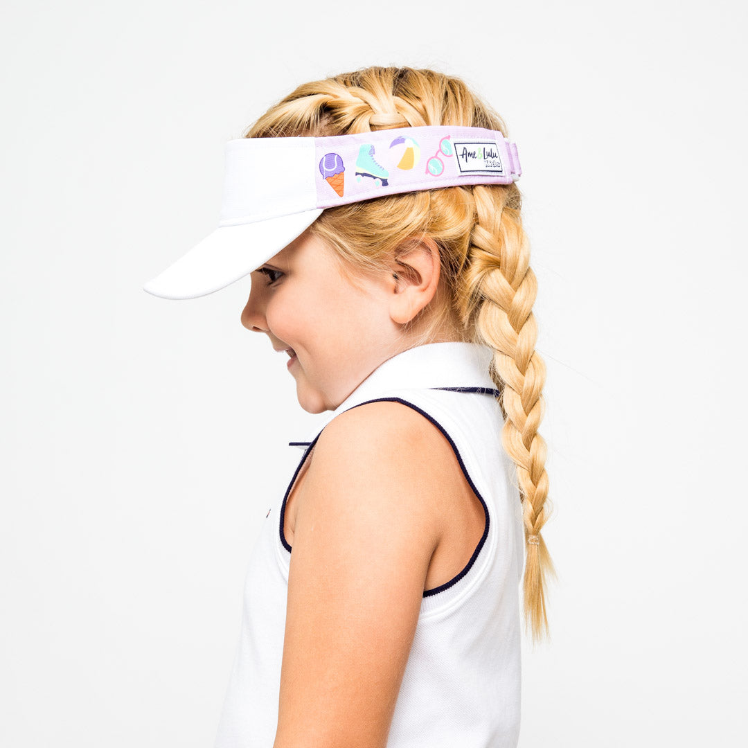 Little girl wearing purple kids visor with ice cream, roller skate, beach ball and sunglasses printed on sides.