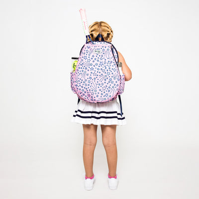 Little girl wearing a light pink kids tennis backpack with pink and purple shooting stars and tennis balls on bag.