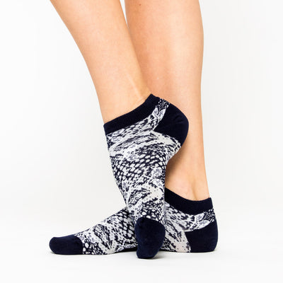 woman wears a pair of grey socks with navy and grey snakeskin and white tennis racquets pattern