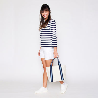 woman holding mini natural canvas tote with light blue and navy cotton webbing straps