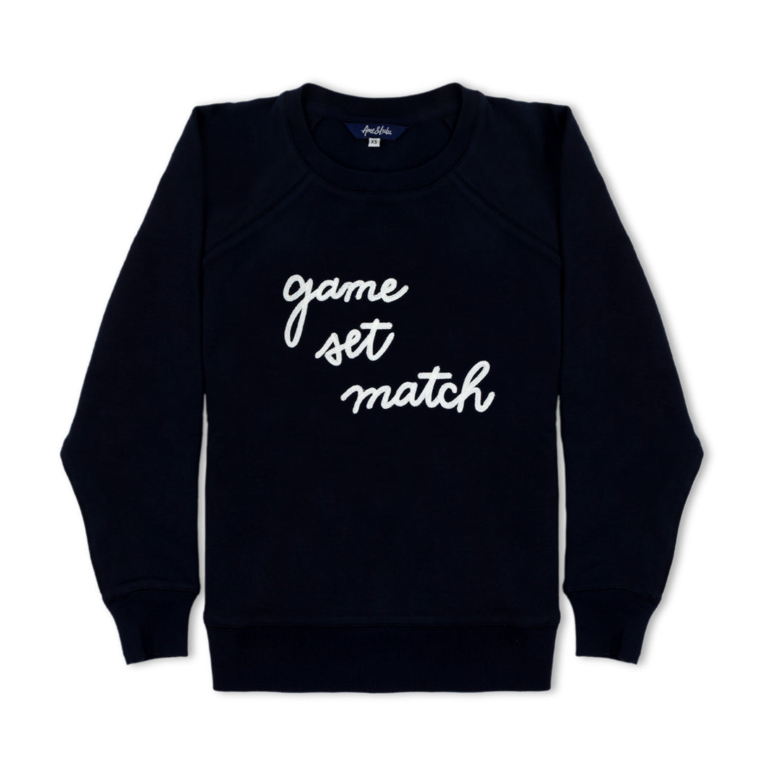Navy womens sweatshirt lays flats with the text game set match in white cursive font across the front of sweatshrit