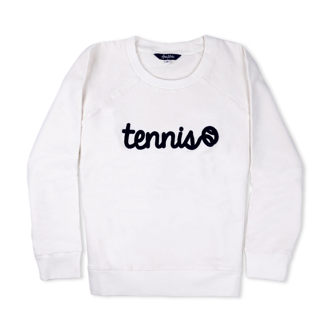 White womens sweatshirt lays flat on white background. There is navy text that reads tennis in a cursive font across front