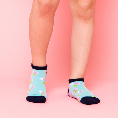 girl wearing pair of light blue kids socks with navy heel and toes with pastel rainbow stitched on socks