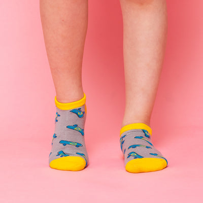 girl wearing pair of grey kids socks with yellow heel and toes with blue skateboards stitched on