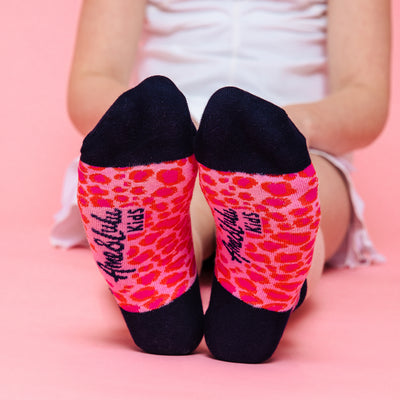 girl wearing pair of hot pink and red leopard pattern kids socks with navy heel and toes