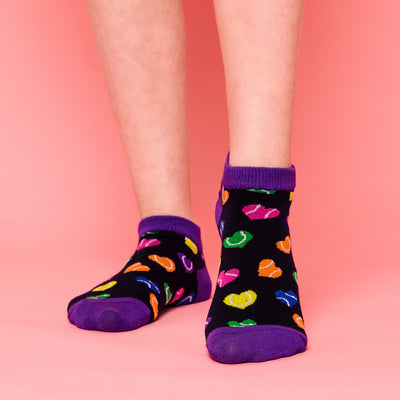 girl wearing pair of navy kids socks with purple heel and toes, and rainbow heart shaped tennis balls stitched on to socks