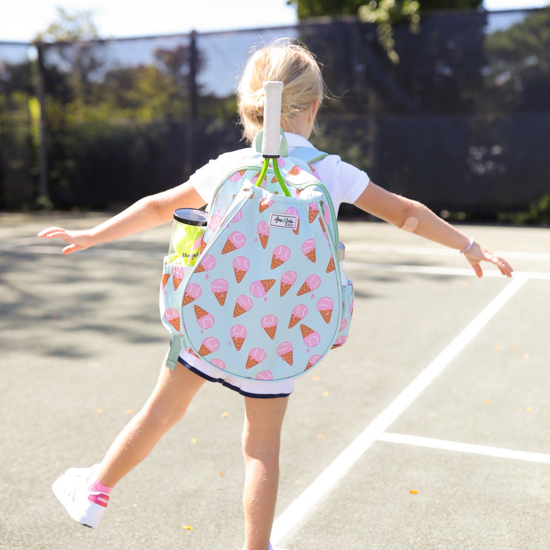 little girl stands on tennis court wearing mint green kids tennis backpack with pink ice cream tennis balls pattern